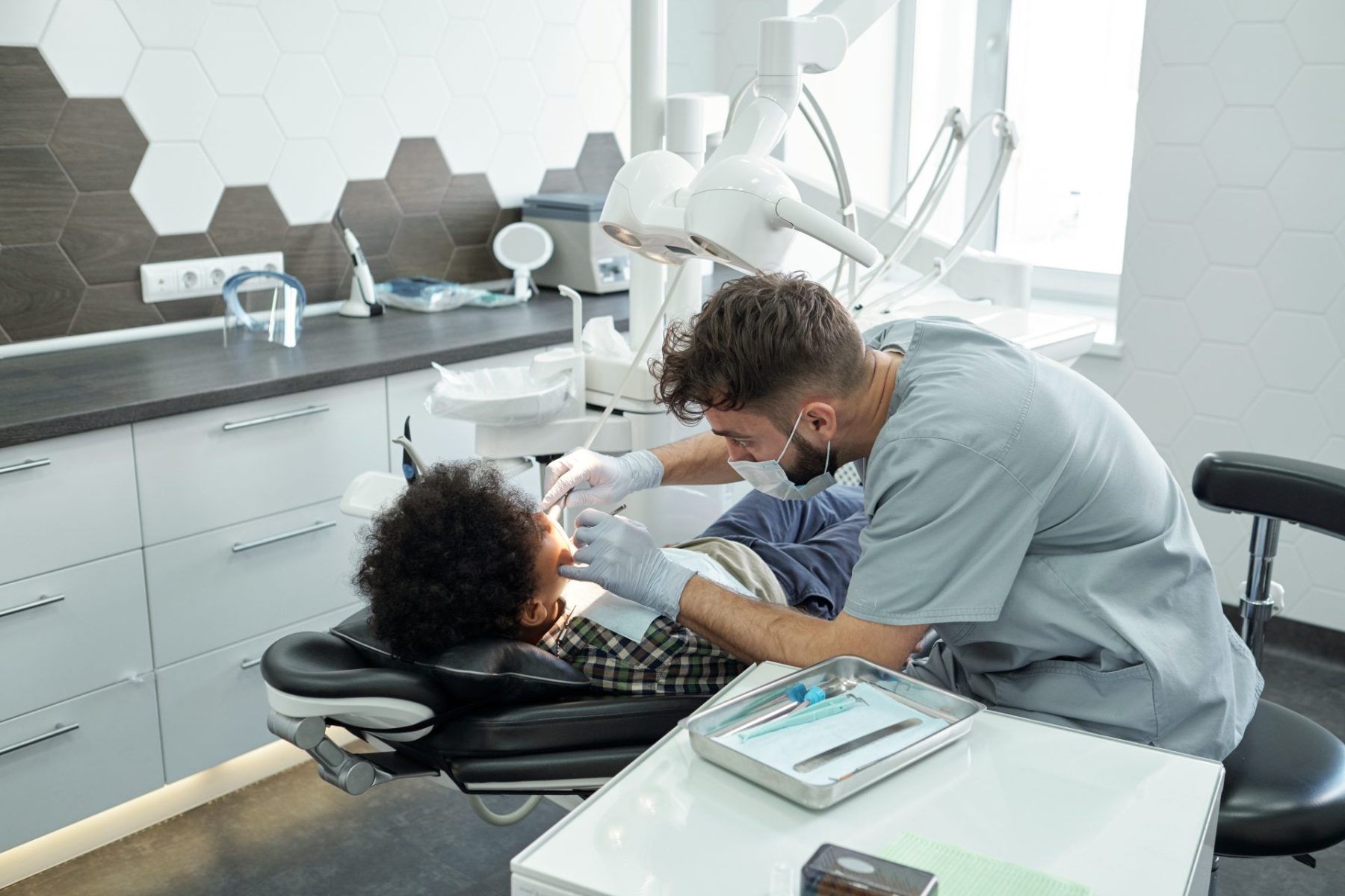 contemporary-dentist-bending-over-little-patient-2023-11-27-05-32-18-utc